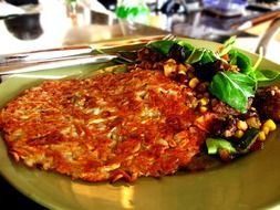 Fried hash browns are on a plate in cafe