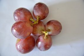 seven grape berries on white surface