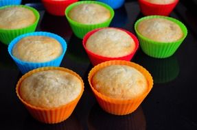 muffins in colorful papers on black surface