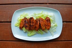 barbecue wings with green salad on white plate