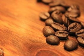 roasted brown coffee grains on a wooden table