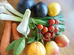 avocado, lemon, orange, apple, leek, carrot and tomatoes on the kitchen table