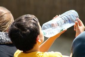 boy drinks water from a bottle on a sunny day