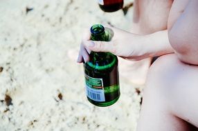 beer in bottle in hand sand view