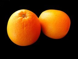 two hybrid citrus fruits on a black background