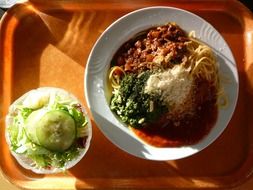 spaghetti with additives in a plate on a tray