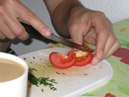 Men is cutting tomato with knife