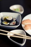 sushi rolls and soy sauce in white ceramic bowls