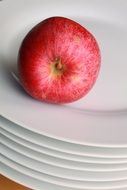 red apple on a stack of white plates