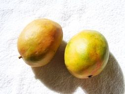 yellowish green mango on the white surface