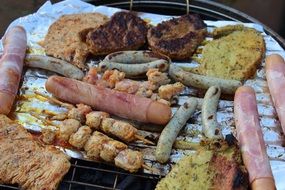 lot of different sausages are roasted on the grill