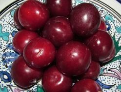 pile of red plums on painted plate