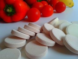 White round vitamin pills and vegetables