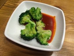 broccoli in sauce on a white plate