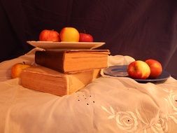 red apples in a plate on the books