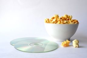 popcorn in a bowl and two audio disc