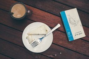 coffee and cake on a plate with the book on the table