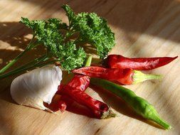 chilli pepper with green leaves on a wooden board