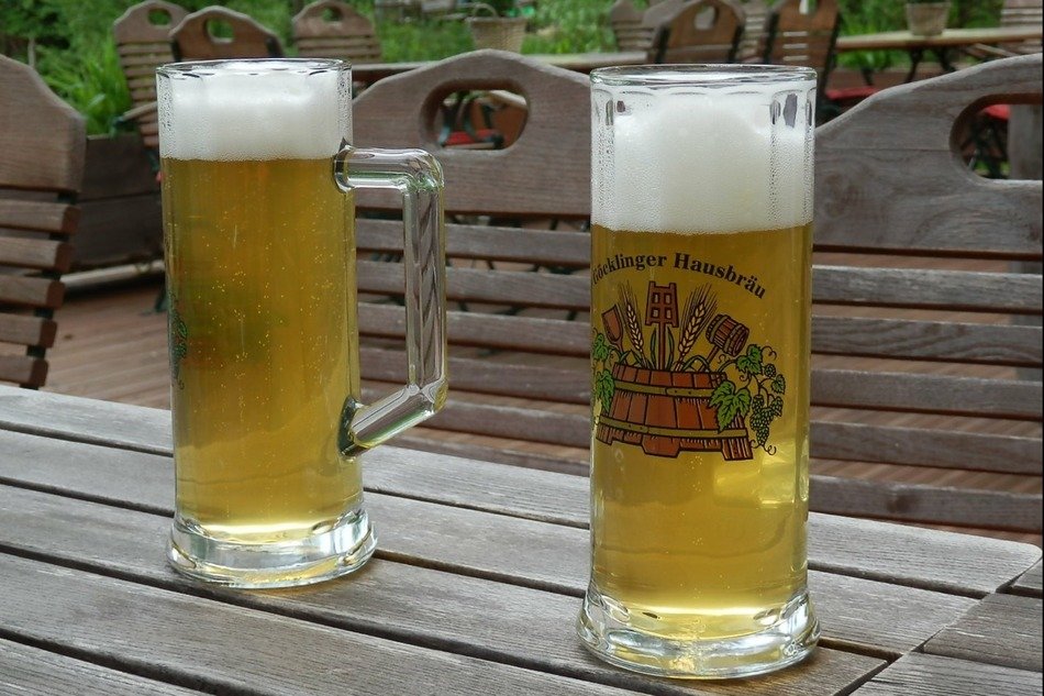 two mugs of cold beer on a wooden table in the open air