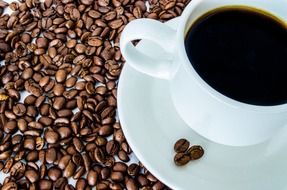 White porcelain cup of coffee and coffee beans