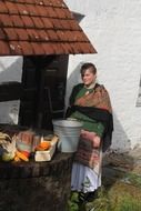 farmer's wife near a well with vegetables