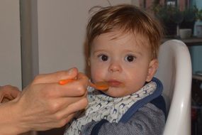 a small baby is fed with a spoon