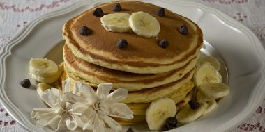 lush pancakes with chocolate and banana on a white plate