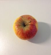 yellow red apple on white table