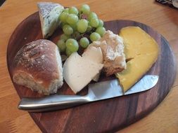 bread, cheese and grapes on a wooden board