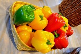 red, green and yellow peppers in a basket on the table