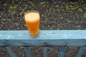 glass of carrot juice on a blue banister