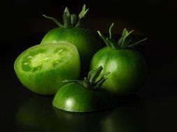 green tomatoes on black background