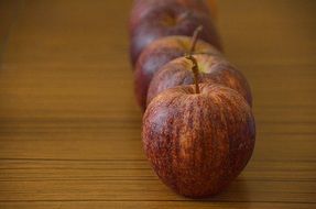 row of red apples on brown surface