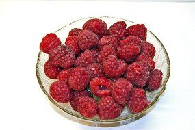 ripe raspberries in a transparent bowl