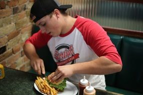 man eating burger with roasted potatoes