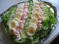 sliced cucumbers, boiled eggs and shrimps on a tray