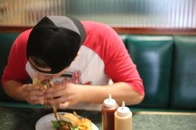 young man eating burger in cafe