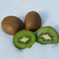 Whole kiwi and slices of kiwi on the snow