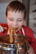 boy eats pasta with tomato sauce