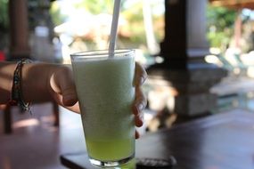 glass with foamy drink in hand