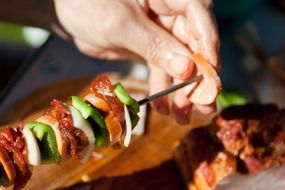 skewer with meat and vegetables in hands