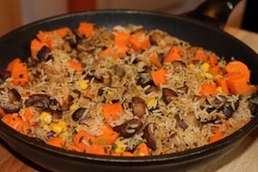 rice with carrots and meat in a black pan