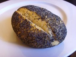 Bun with poppy seeds on a white plate