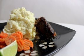 steak dinner on a black plate close up