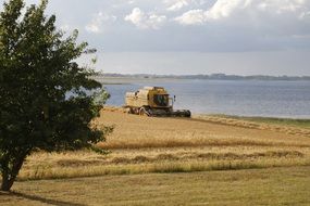 panoramic view of a combine harvester on farmland on a sunny day