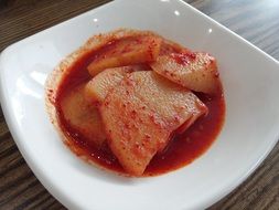 Boiled spicy potatoes with red pepper on a white plate