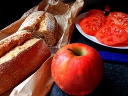 bread, red apple and sliced tomatoes on table