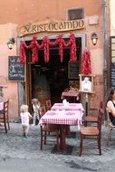 kids playing in outdoor resaurant between tables with checkered tablecloth, italy, rome