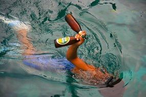 a young man under the water is holding two beer bottles