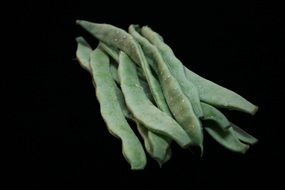 pods of green beans on black